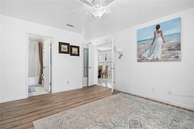 119 Misty Ln, Aransas Pass, TX 78336 - unfurnished bedroom featuring wood finished floors, baseboards, connected bathroom, and a ceiling fan