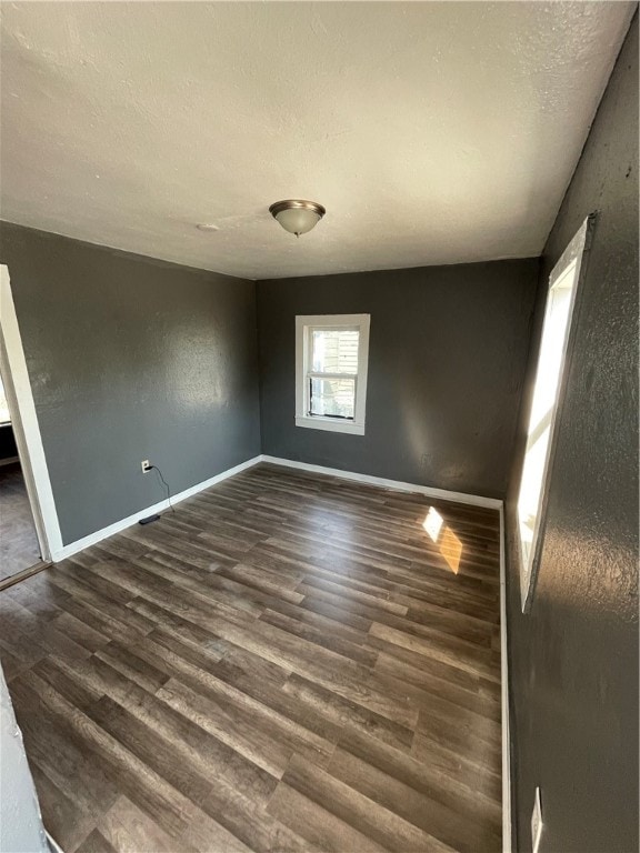 empty room with a textured ceiling and dark hardwood / wood-style floors