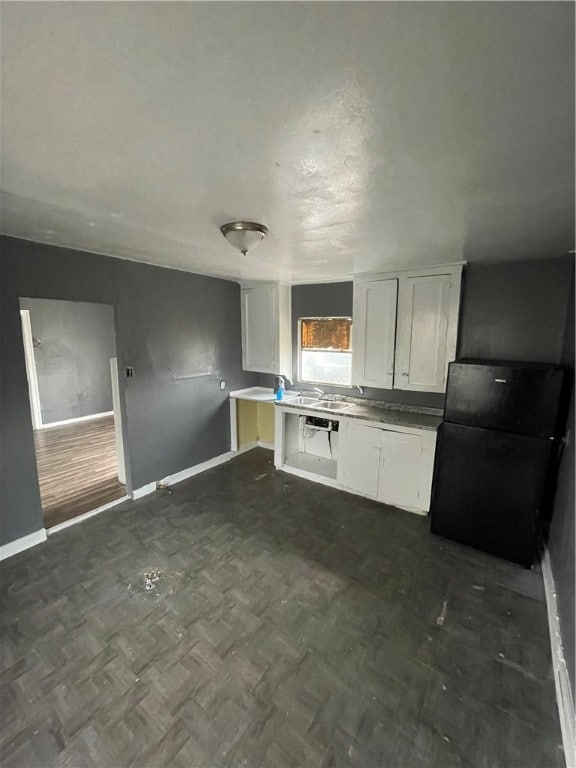 kitchen with black refrigerator, white cabinets, and sink