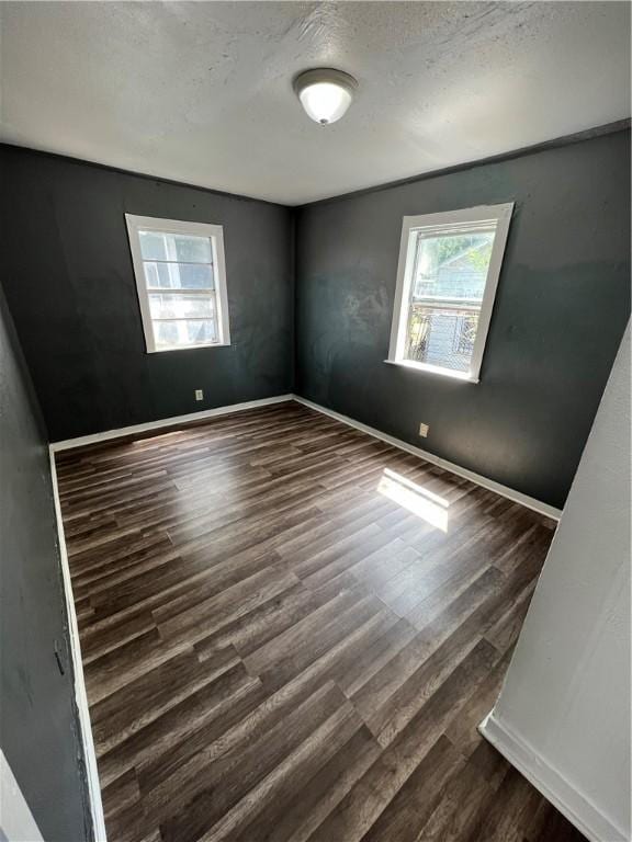 unfurnished room with a textured ceiling, plenty of natural light, and dark wood-type flooring