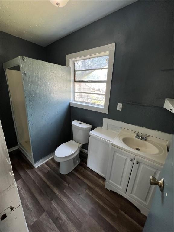 bathroom with hardwood / wood-style flooring, vanity, toilet, and a shower