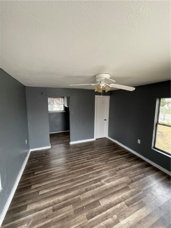 empty room with ceiling fan, dark hardwood / wood-style flooring, and a textured ceiling