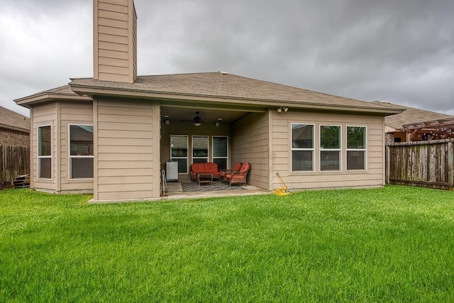 rear view of property with a lawn, ceiling fan, a chimney, fence, and a patio area