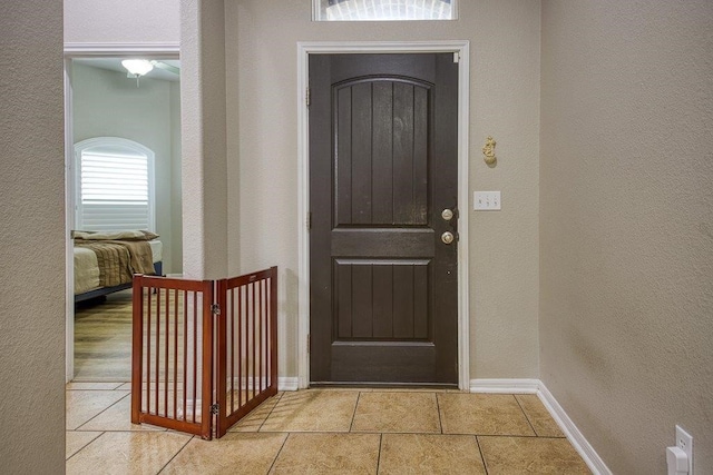 entryway with a textured wall, tile patterned floors, and baseboards