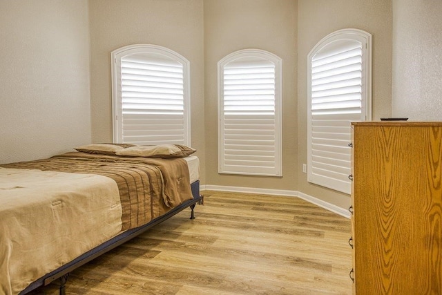 bedroom featuring light wood finished floors and baseboards