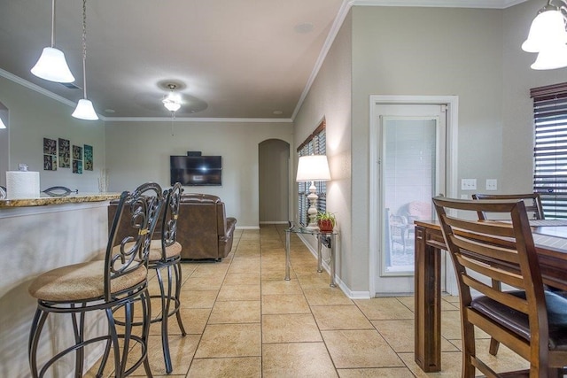 kitchen with light tile patterned floors, baseboards, arched walkways, and ornamental molding