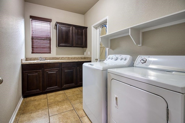 laundry room with washer and clothes dryer, light tile patterned floors, cabinet space, a sink, and baseboards