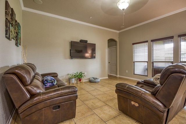 living area with light tile patterned floors, baseboards, arched walkways, ceiling fan, and crown molding