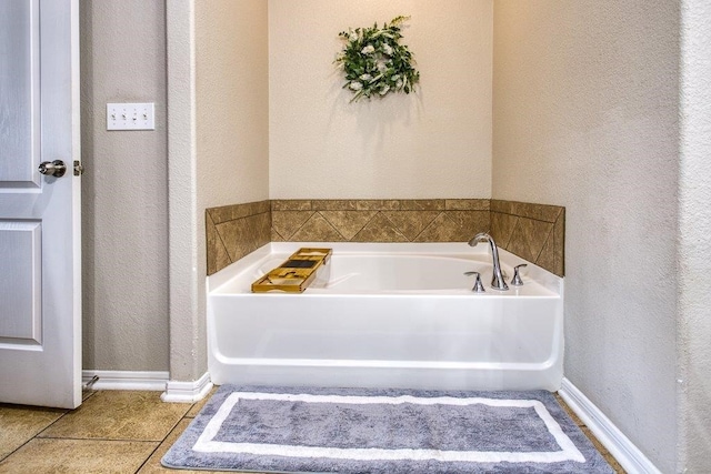 full bath with a garden tub, tile patterned flooring, baseboards, and a textured wall