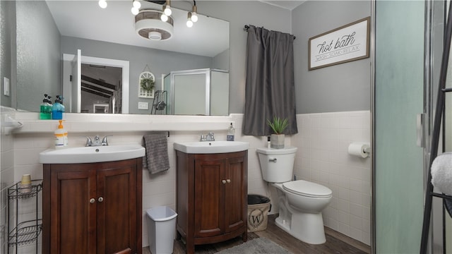 bathroom featuring toilet, tile walls, hardwood / wood-style flooring, vanity, and a shower with shower door