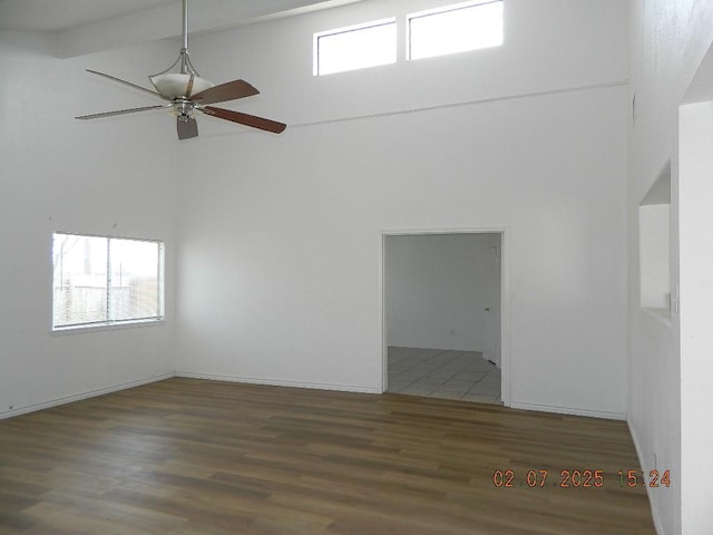 unfurnished room featuring a towering ceiling, wood-type flooring, and ceiling fan