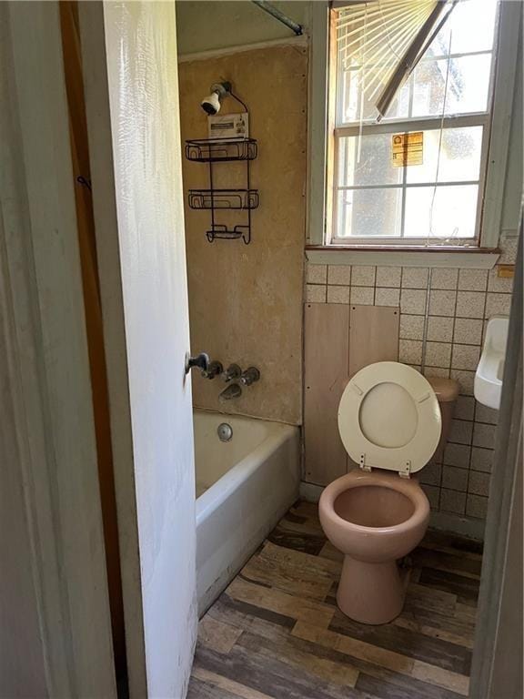 bathroom featuring tub / shower combination, tile walls, toilet, and wood finished floors