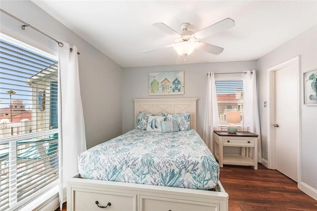 bedroom with ceiling fan, dark wood-type flooring, and multiple windows