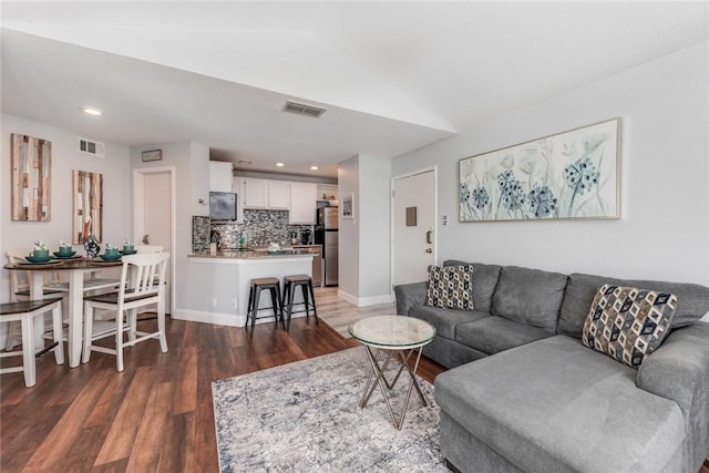 living room with dark hardwood / wood-style flooring and vaulted ceiling