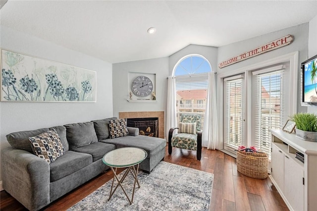 living room with lofted ceiling, dark wood-type flooring, and a tiled fireplace