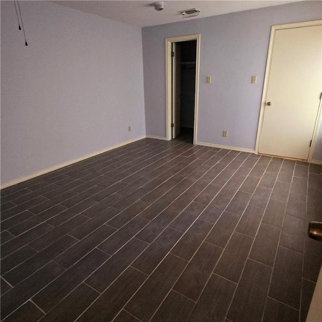 spare room featuring wood tiled floor, visible vents, and baseboards