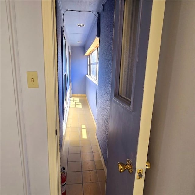 corridor with a textured wall and tile patterned floors