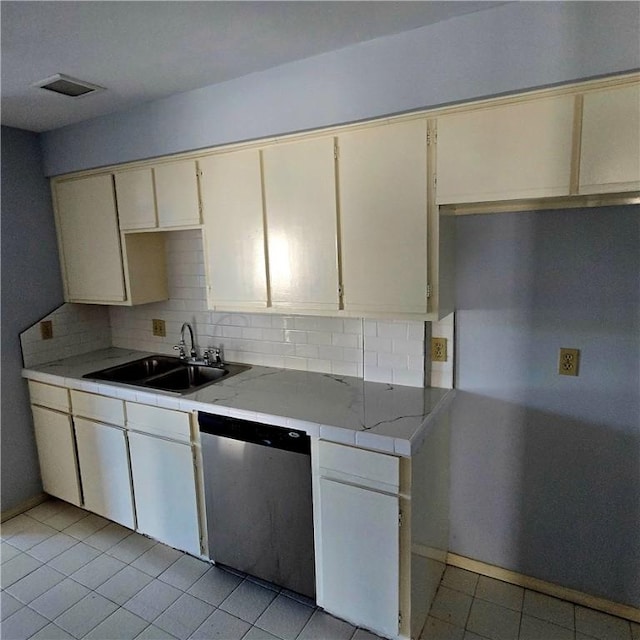 kitchen with dishwasher, backsplash, a sink, and light tile patterned floors