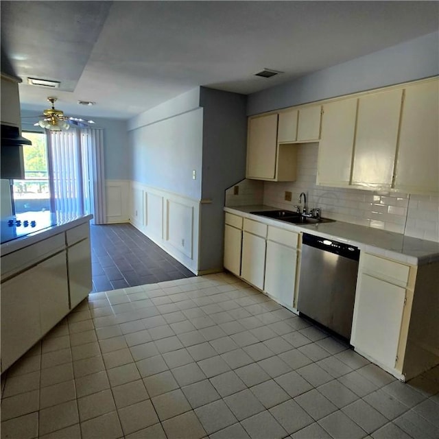 kitchen with tasteful backsplash, a wainscoted wall, light countertops, stainless steel dishwasher, and a sink