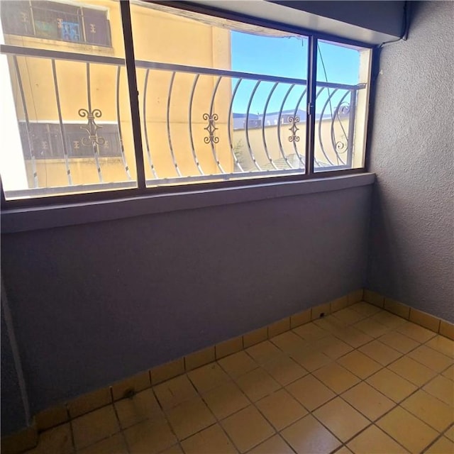 unfurnished room with tile patterned flooring, baseboards, and a textured wall