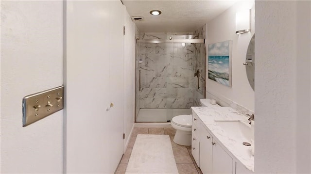 bathroom featuring toilet, vanity, tile patterned floors, and a shower with door