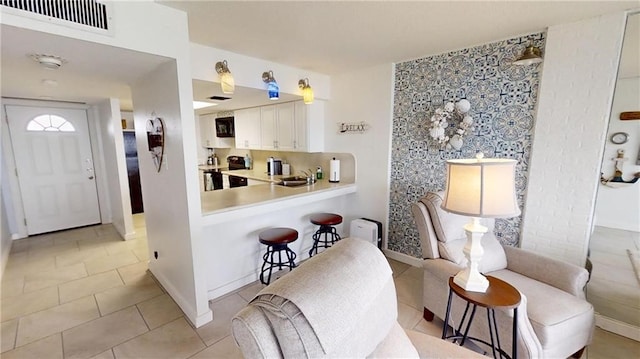 kitchen with a kitchen bar, white cabinets, kitchen peninsula, sink, and stainless steel electric range oven