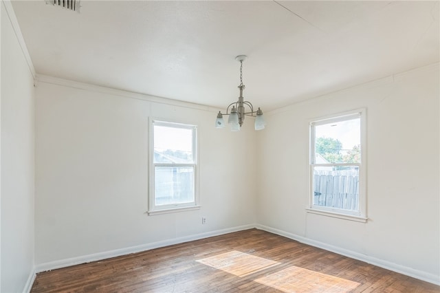 spare room featuring hardwood / wood-style flooring, a notable chandelier, and a healthy amount of sunlight