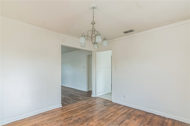 spare room featuring dark hardwood / wood-style flooring, an inviting chandelier, and crown molding