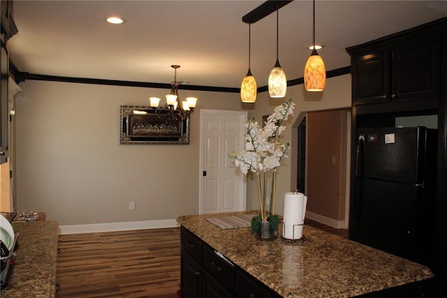 kitchen with dark wood-type flooring, black fridge, an inviting chandelier, decorative light fixtures, and ornamental molding