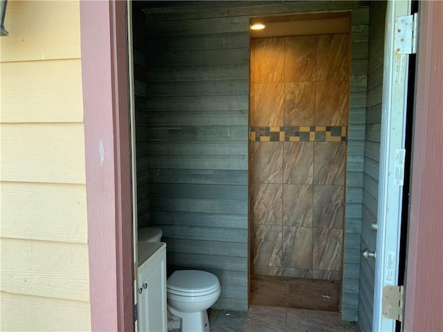 bathroom with vanity, toilet, and wood walls