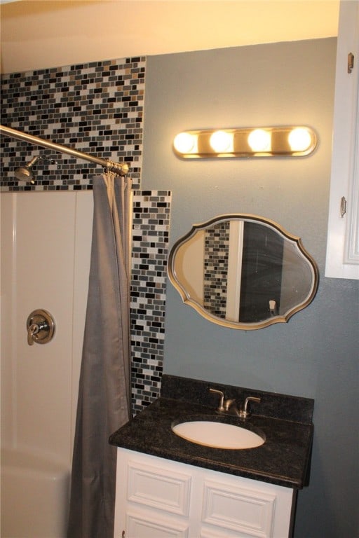 bathroom featuring walk in shower, vanity, and backsplash