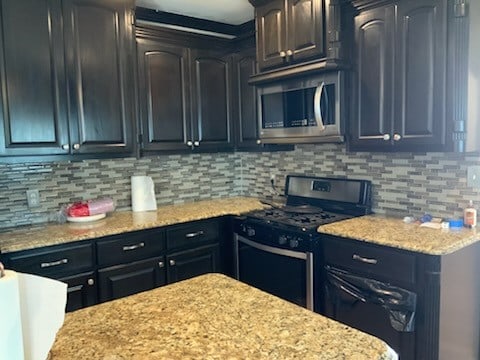 kitchen featuring backsplash, stainless steel appliances, and light stone countertops