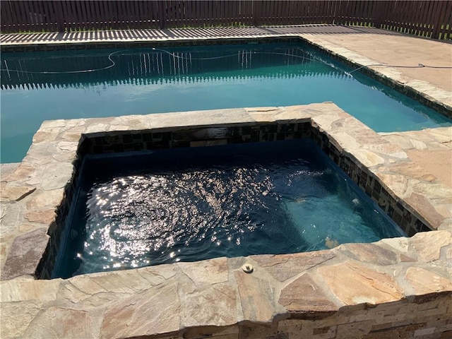 view of swimming pool with an in ground hot tub