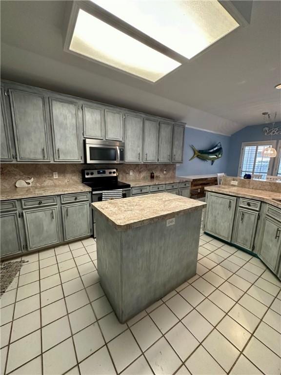 kitchen featuring a center island, light countertops, lofted ceiling, light tile patterned floors, and appliances with stainless steel finishes