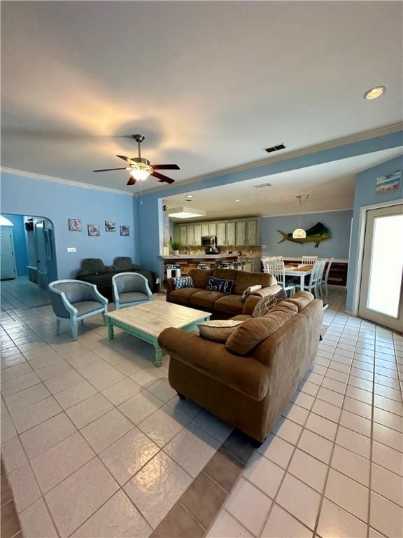 living room featuring ceiling fan, visible vents, light tile patterned flooring, and ornamental molding