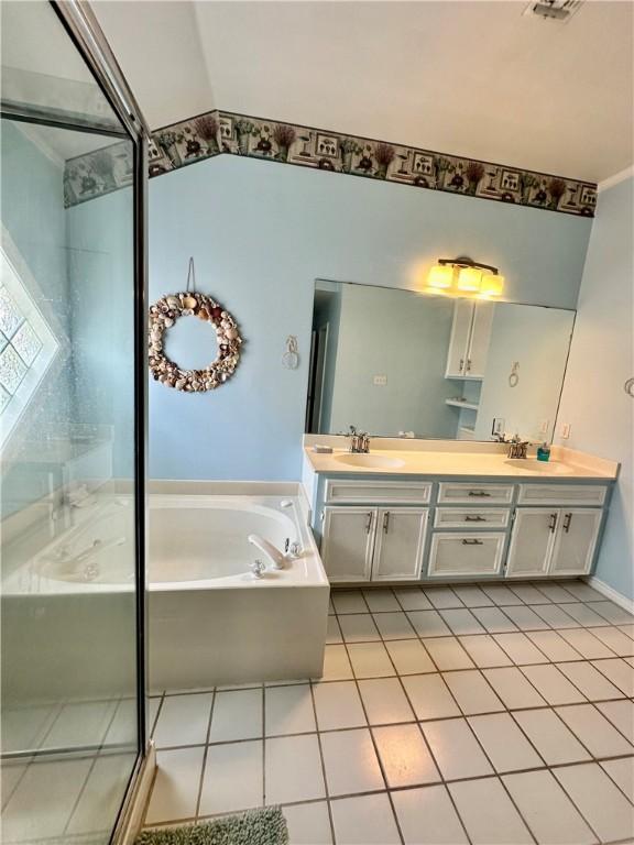 bathroom featuring tile patterned floors, a garden tub, a sink, double vanity, and lofted ceiling