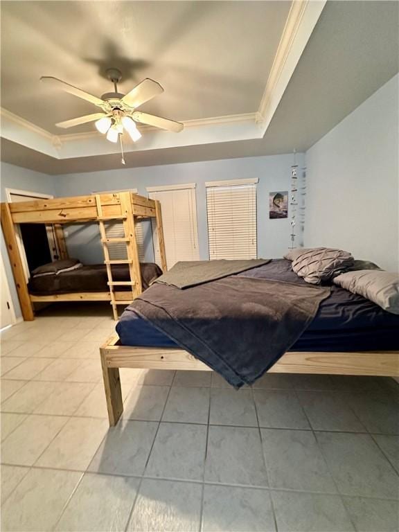 bedroom featuring a ceiling fan, a tray ceiling, light tile patterned flooring, and crown molding