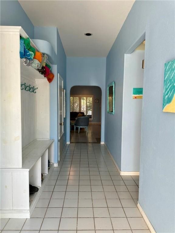 mudroom with arched walkways, baseboards, and light tile patterned flooring