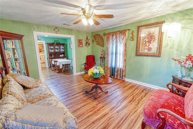 sitting room with ceiling fan, a textured ceiling, and light wood-type flooring