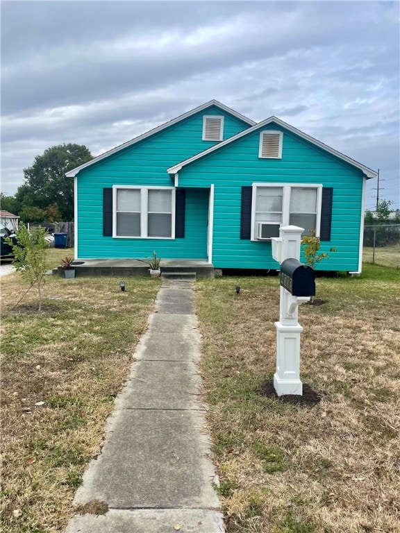 view of front of house featuring cooling unit and a front lawn