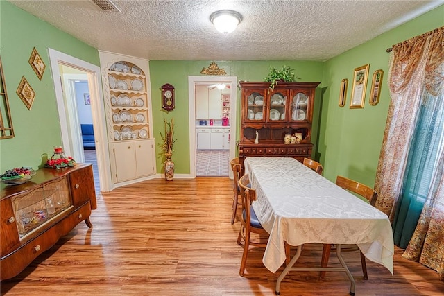 dining room with a textured ceiling and light wood-type flooring