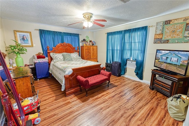 bedroom with ceiling fan, hardwood / wood-style floors, and a textured ceiling