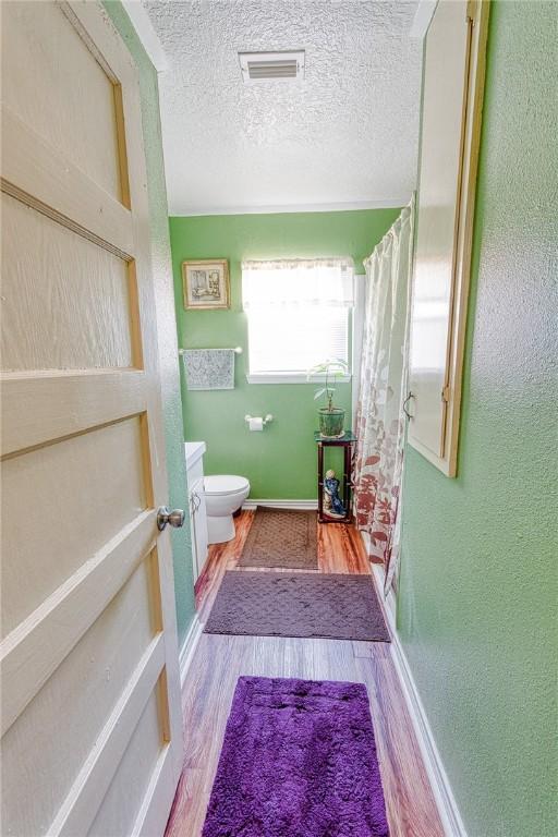 bathroom featuring toilet, a shower with curtain, a textured ceiling, vanity, and hardwood / wood-style floors