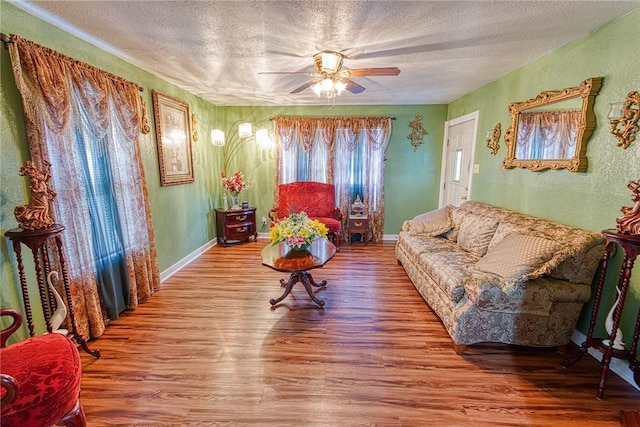 living room with wood-type flooring, ceiling fan, and a textured ceiling