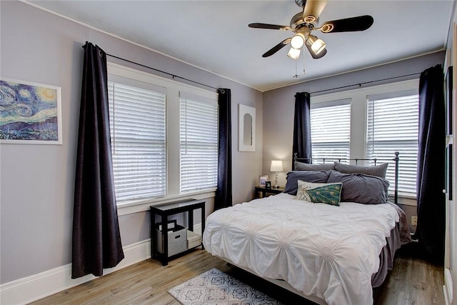 bedroom with ceiling fan, light wood finished floors, and baseboards