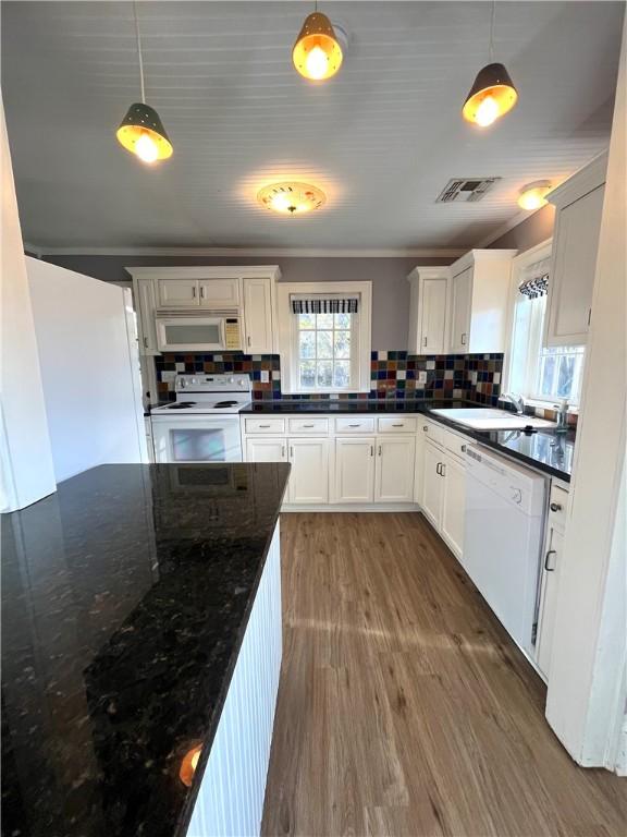 kitchen featuring white appliances, a sink, wood finished floors, visible vents, and tasteful backsplash