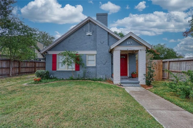 bungalow-style home with a front yard, fence, and a chimney