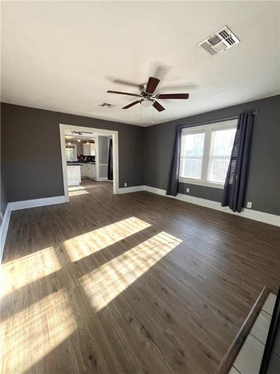 empty room with wood finished floors, visible vents, and baseboards