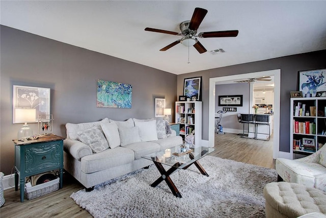 living area featuring ceiling fan, wood finished floors, visible vents, and baseboards