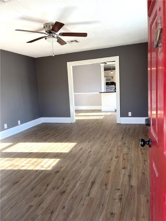 spare room featuring wood finished floors, visible vents, and baseboards